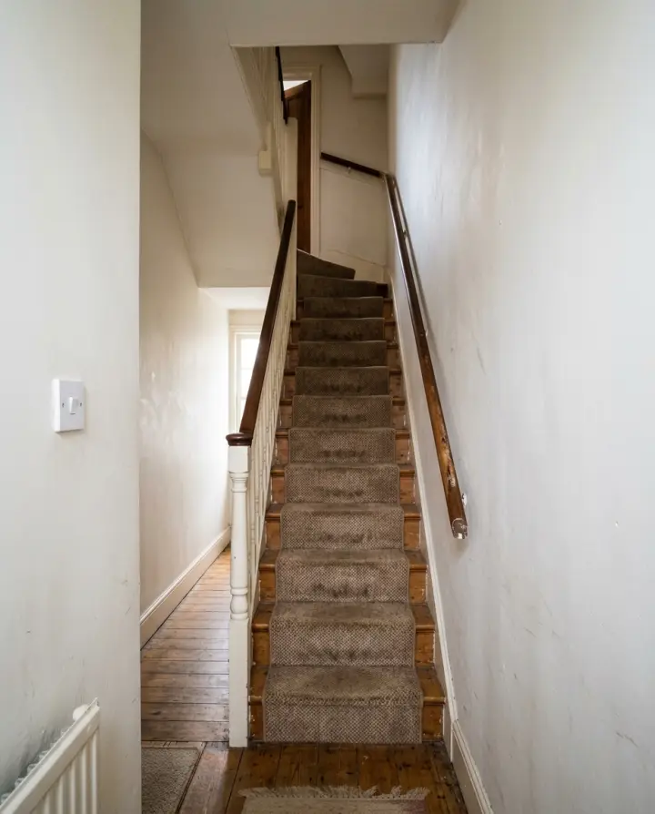 A customer’s photo of the way in: a narrow, straight, carpeted staircase between a banister and a wall.